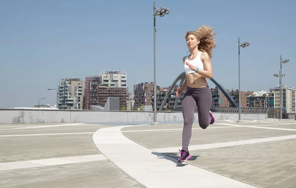 Fit woman running in urban environment in summer — Stock Photo, Image