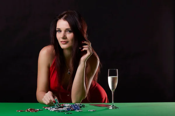 Молодая брюнетка играет в покер на черном фоне — стоковое фото