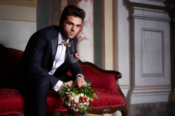Young groom waiting his bride on sofa — Stock Photo, Image