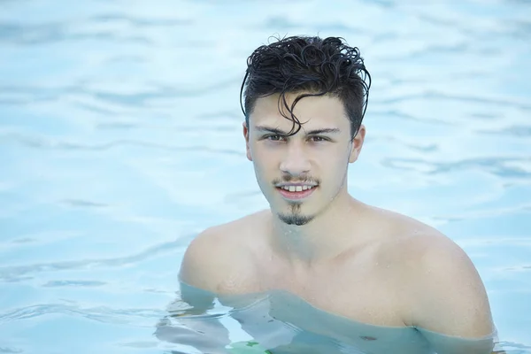 Happy attractive man standing in blue water in a swimming pool — Stock Photo, Image