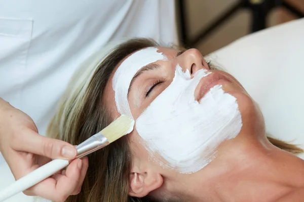 Mooie jonge vrouw met een gezicht cosmetische masker in spa salon — Stockfoto
