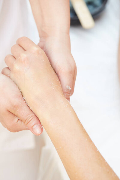 Woman Getting a Salt Scrub Beauty Treatment on hands in the Health Spa