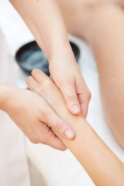 Mujer recibiendo un tratamiento de belleza con exfoliante de sal en las manos en el spa de salud —  Fotos de Stock