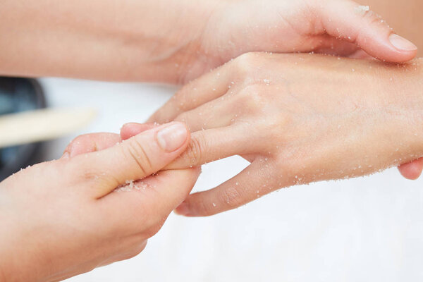 Woman Getting a Salt Scrub Beauty Treatment on hands in the Health Spa