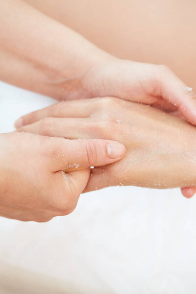Woman Getting a Salt Scrub Beauty Treatment on hands in the Health Spa