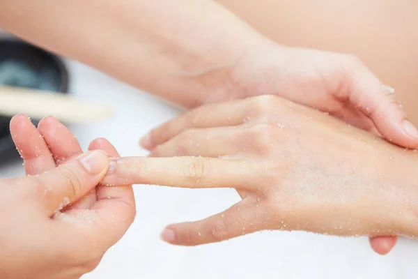 Mujer recibiendo un tratamiento de belleza con exfoliante de sal en las manos en el spa de salud —  Fotos de Stock