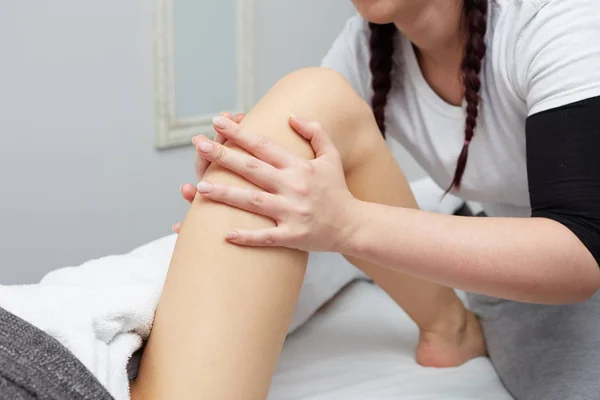 Terapeuta aplicando presión sobre la pierna femenina — Foto de Stock