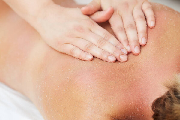 Beautiful blonde enjoying a salt scrub treatment at the health spa