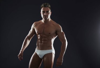 Yakışıklı kaslı genç adam stüdyo arka plan üzerinde uygun. 