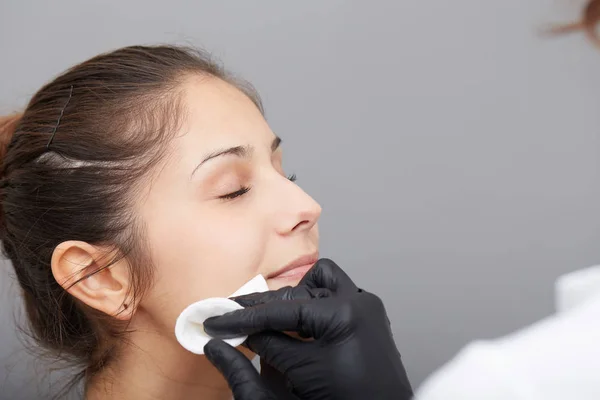 Kosmetikerin schminkt das Gesicht einer Frau dauerhaft — Stockfoto