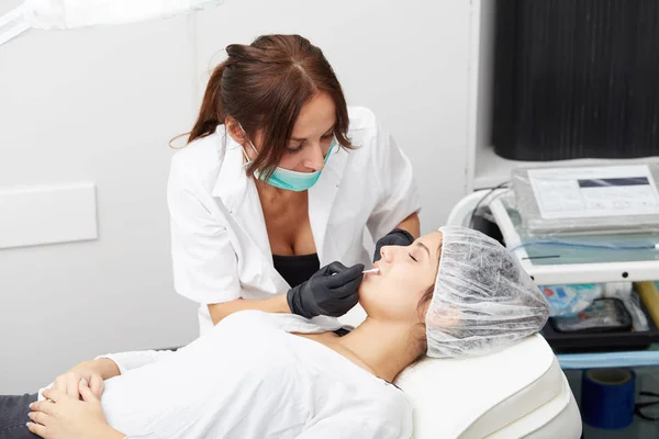 Cosmetologist καθιστώντας μόνιμη μακιγιάζ στο πρόσωπό της γυναίκας — Φωτογραφία Αρχείου