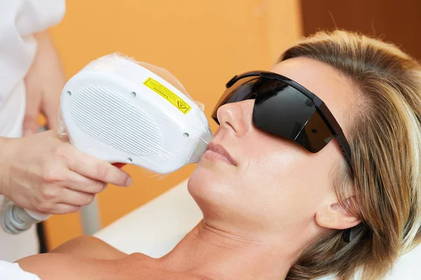 Esteticista dando tratamento de compilação a laser para o corpo da mulher jovem na clínica de beleza — Fotografia de Stock