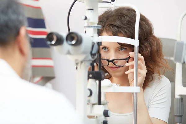 Mooie jonge vrouw met haar ogen onderzocht door een oogarts — Stockfoto