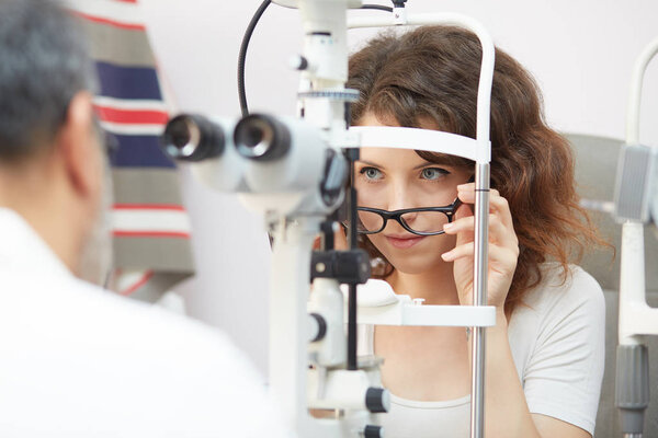 pretty young woman having her eyes examined by an eye doctor