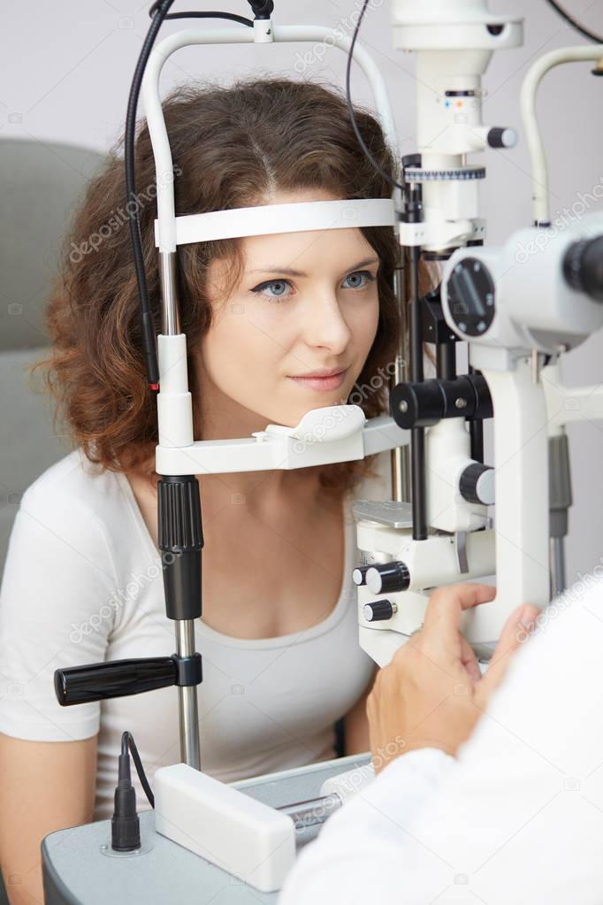 pretty young woman having her eyes examined by an eye doctor