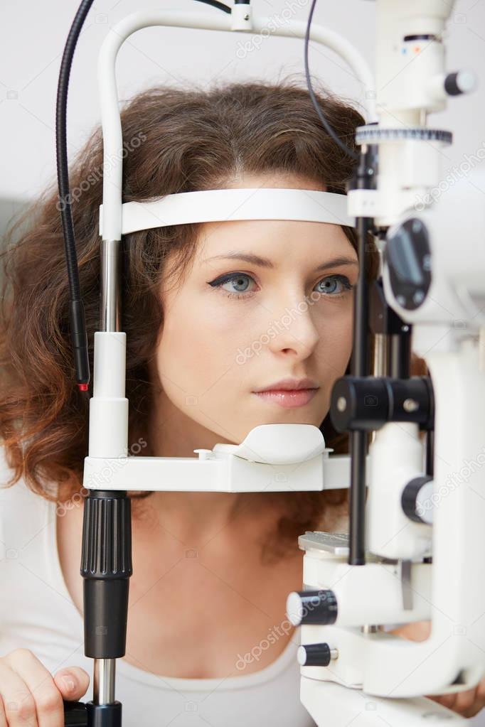 pretty young woman having her eyes examined by an eye doctor
