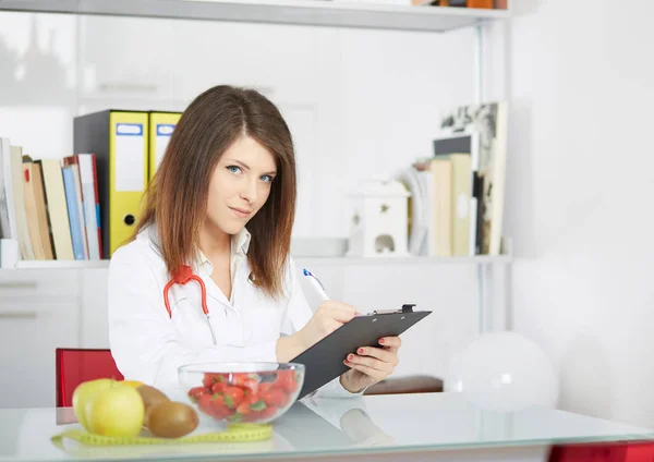 Foto conceptual de una nutricionista femenina con frutas en el escritorio —  Fotos de Stock