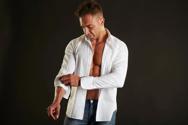 Close up of sporty man posing in white shirt over black background — Stock Photo, Image