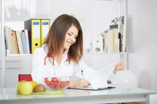 Smiling doctor nutritionist  sitting at the desk — Stock Photo, Image