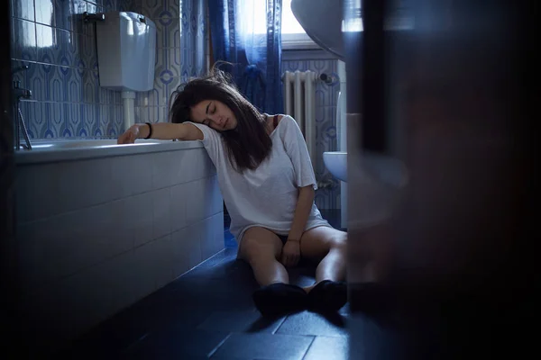 Menina viciada inconsciente sentado no chão do banheiro — Fotografia de Stock