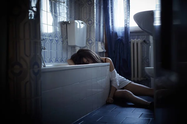 Chica adicta inconsciente sentado en el suelo del baño —  Fotos de Stock