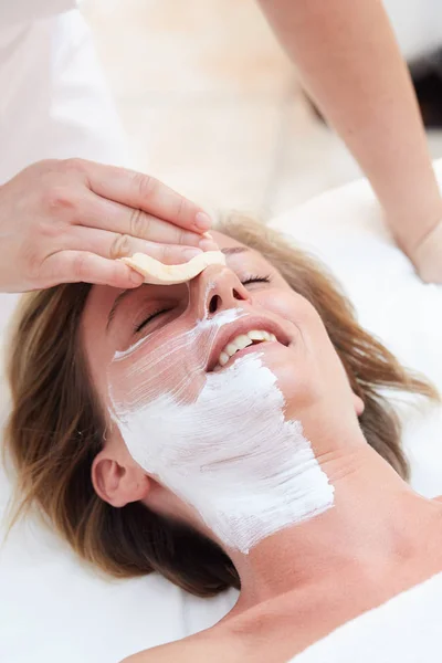 Beautiful woman with clear skin getting facial mask at salon