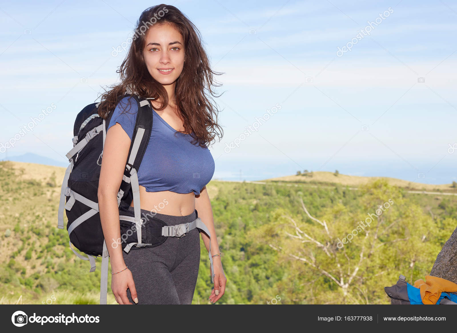 Woman hiker smiling and walking with hiking poles. Stock Photo by