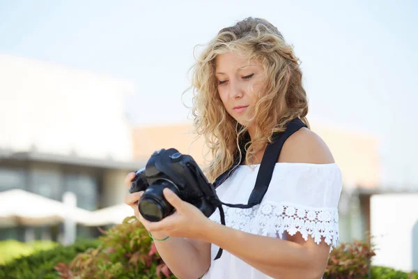 Portrait of attractive girl holding a camera outdoors — Stock Photo, Image