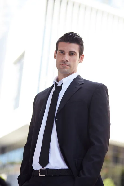 Hombre de negocios guapo de pie fuera del edificio de oficinas — Foto de Stock