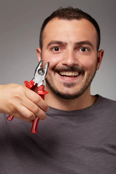 fool man showing pliers and make a bizarre face