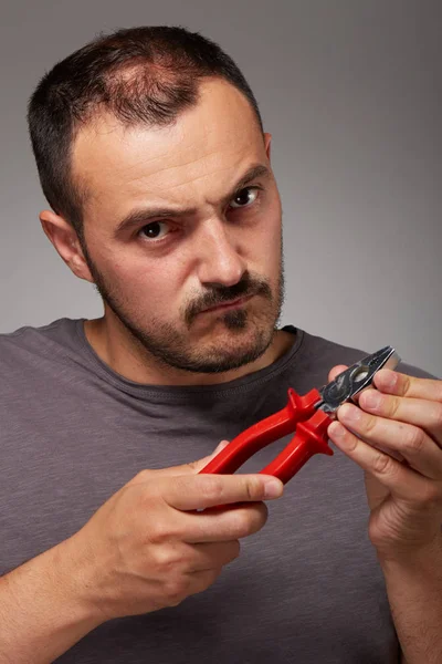 Homem tolo mostrando alicates e fazer uma cara bizarra — Fotografia de Stock