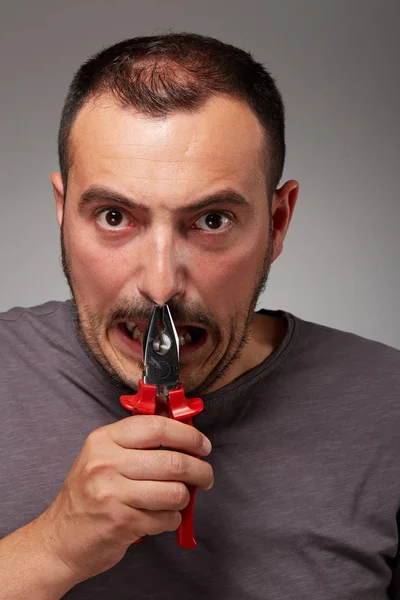 fool man showing pliers and make a bizarre face
