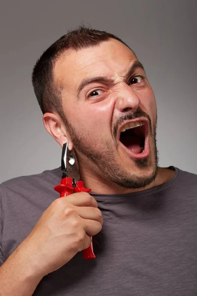 Hombre tonto mostrando alicates y hacer una cara extraña —  Fotos de Stock