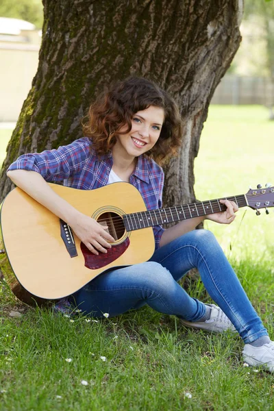Vrouw spelen gitaar in park — Stockfoto