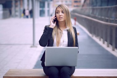 dizüstü bilgisayar kullanarak ve kentsel çevre için mobil konuşmak güzel iş kadını