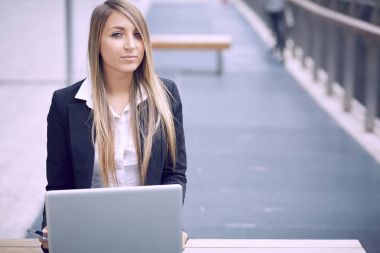 dizüstü bilgisayar kullanarak ve kentsel çevre için mobil konuşmak güzel iş kadını