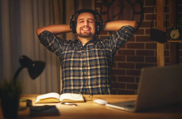 Man in de koptelefoon op de computer's avonds in het donker naar huis — Stockfoto