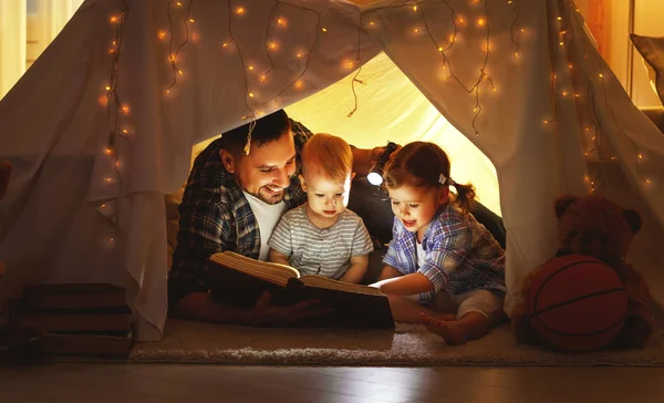 Feliz familia padre e hijos leyendo un libro en tienda en hom — Foto de Stock