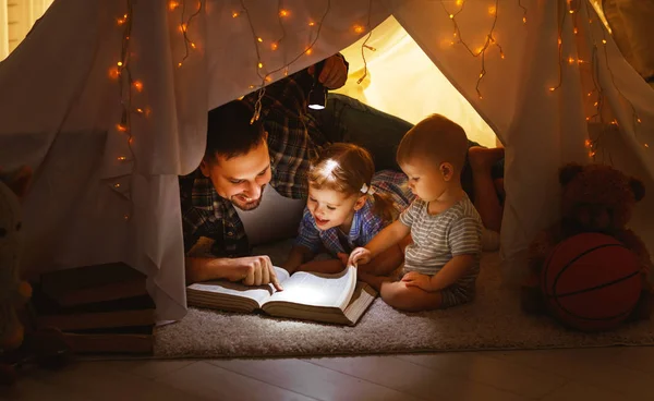 Szczęśliwy ojciec rodziny i dzieci, czytanie książki w namiocie w hom — Zdjęcie stockowe