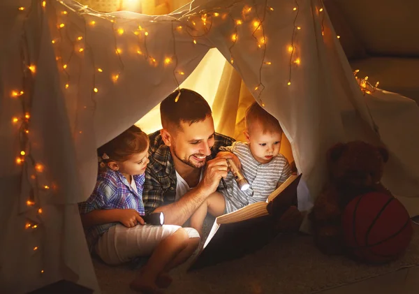 Glücklicher Familienvater und Kinder lesen im Zelt bei hom ein Buch — Stockfoto