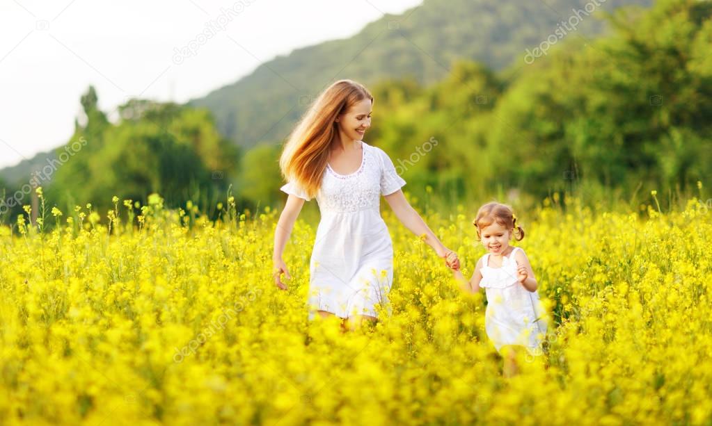 Happy family mother and child daughter running in  nature in sum