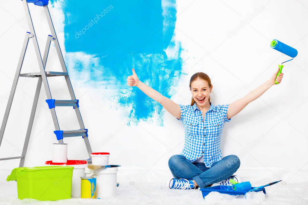 Repair in apartment. Happy woman paints wall 