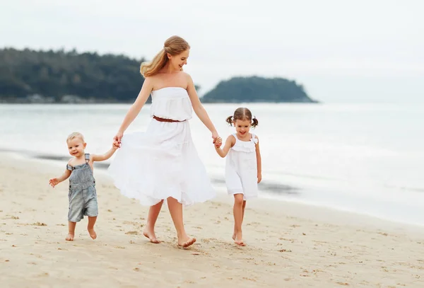 Happy family mother and children on beach by sea in summer — Stock Photo, Image