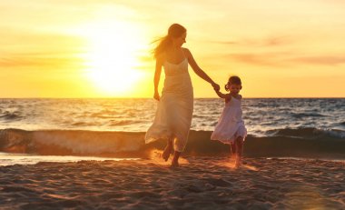 mutlu aile anne ve kızı çalıştırmak, gülmek ve plajda oyna