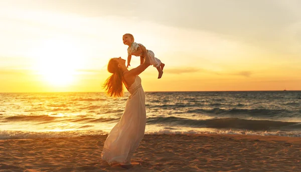 Feliz familia madre con bebé hijo camina por el océano en la playa en suma —  Fotos de Stock