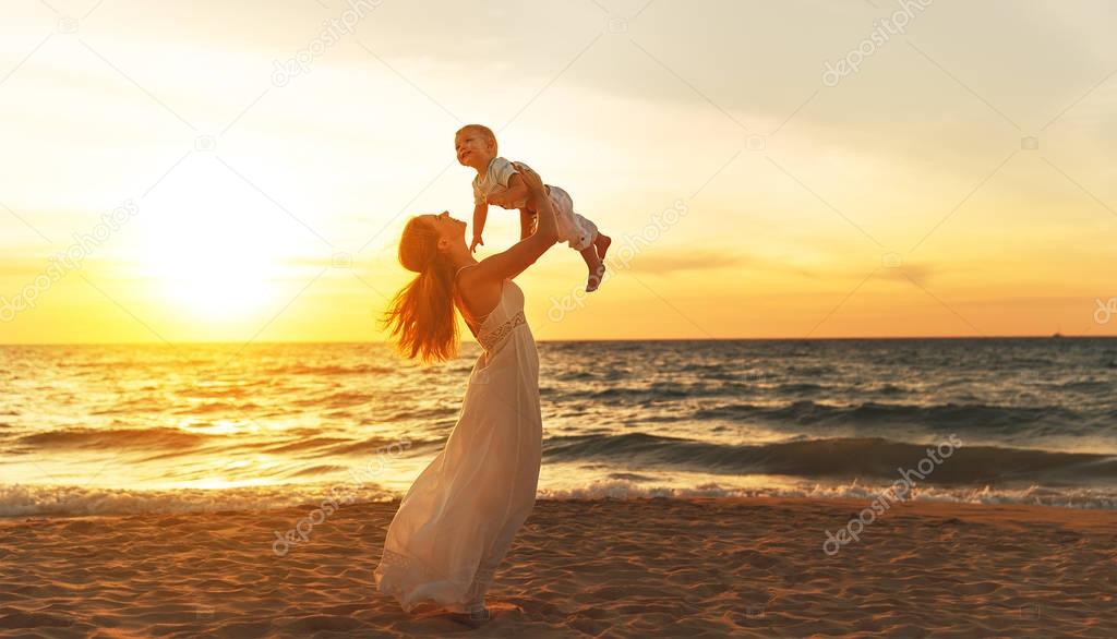 happy family mother with baby son walks by ocean on beach in sum