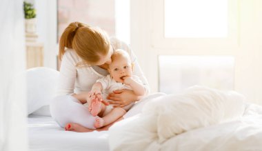 Mutlu aile anne ve bebek oynamak, yatakta sarılma