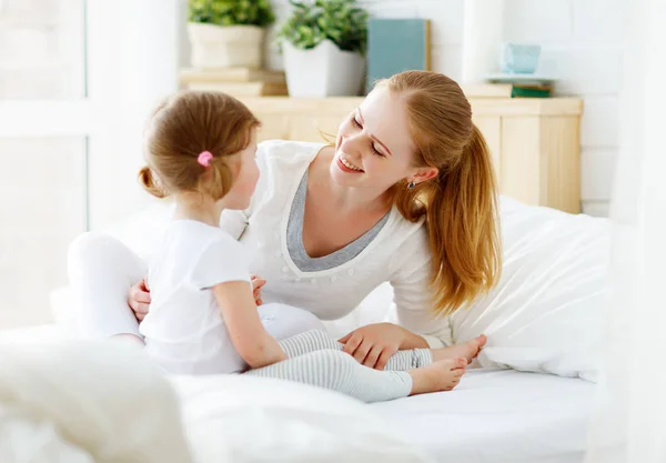 Glückliche Familienmutter und kleine Tochter spielen im Bett — Stockfoto