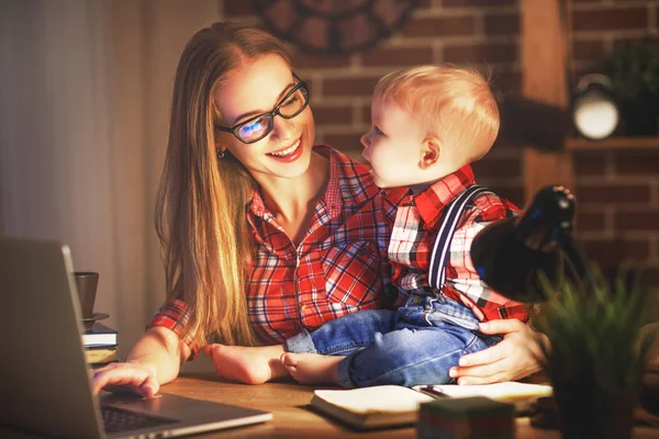Mujer madre trabajando con un bebé en casa detrás de un cálculo —  Fotos de Stock