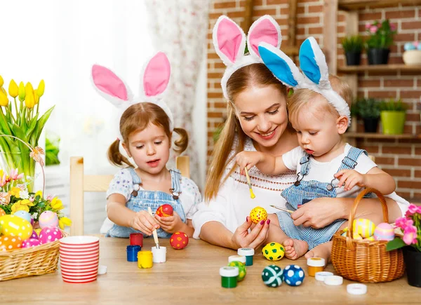 Happy easter! family mother and children paint eggs for holiday